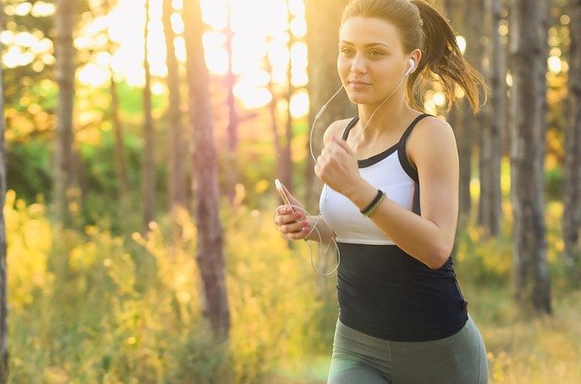 Image of woman running outside with earphones - Coffeyfit.com